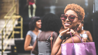 Woman with Purple Shopping Bag Smiling wearing Sunglasses