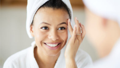 Woman smiling in mirror while checking her skin