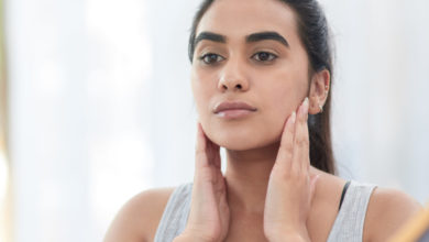 A woman applying skin cream to her cheeks