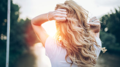 Woman facing into sun holding her wavy hair