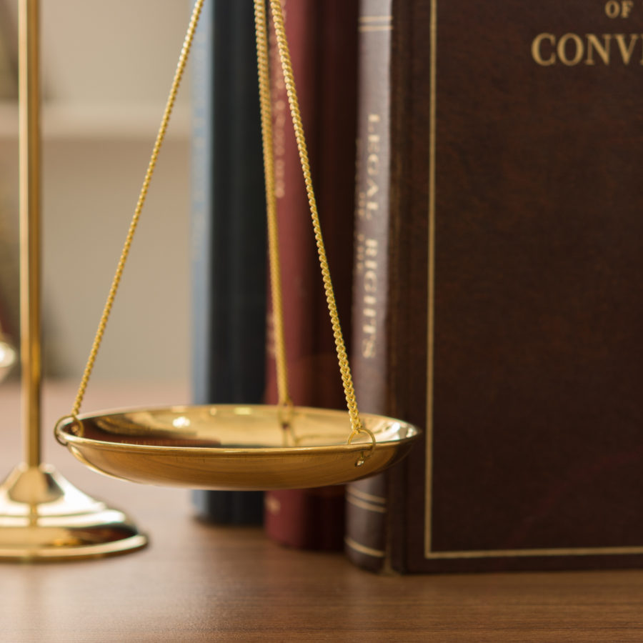 Gold balance scales with old books behind