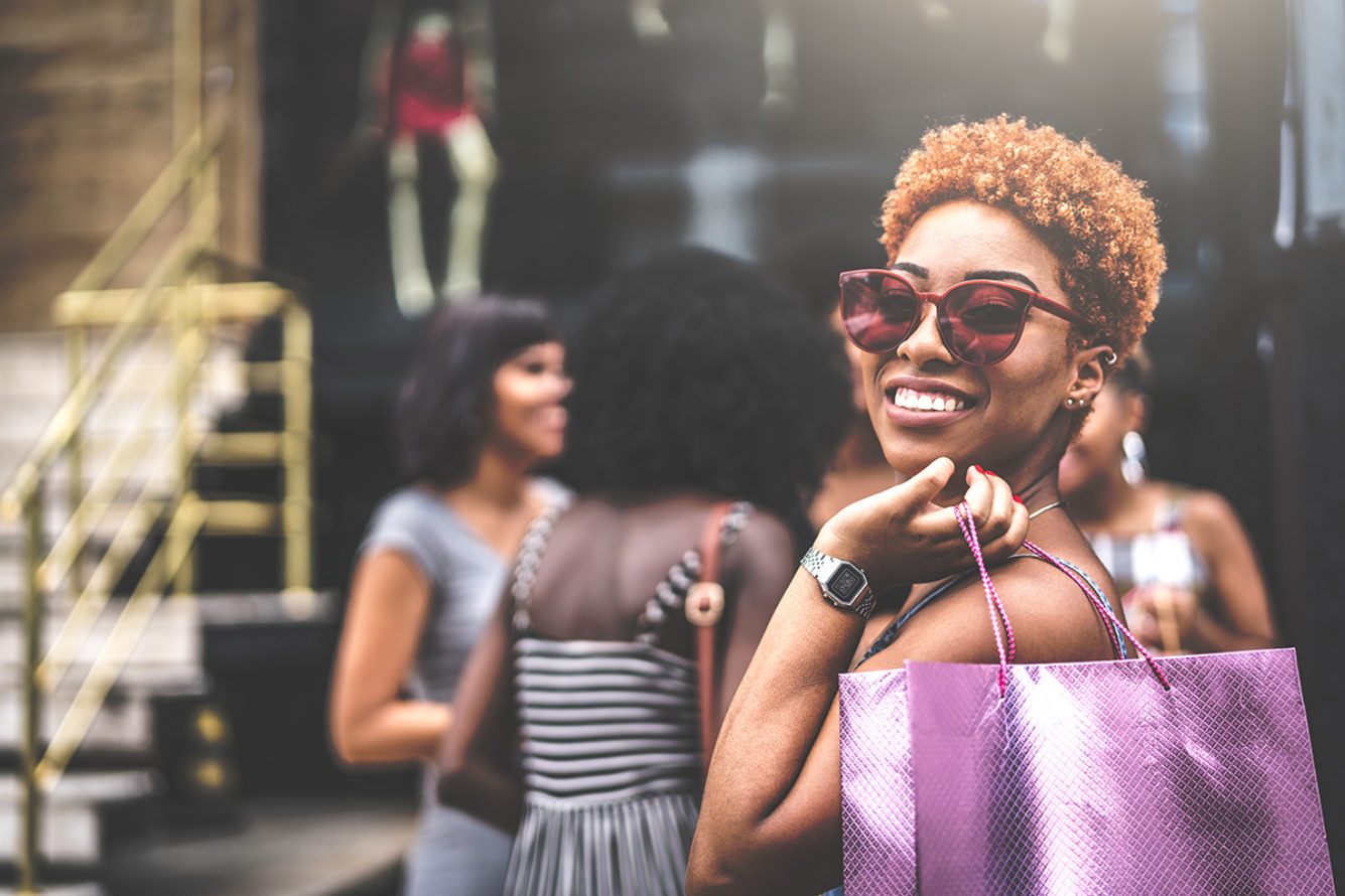 Woman with Purple Shopping Bag Smiling wearing Sunglasses