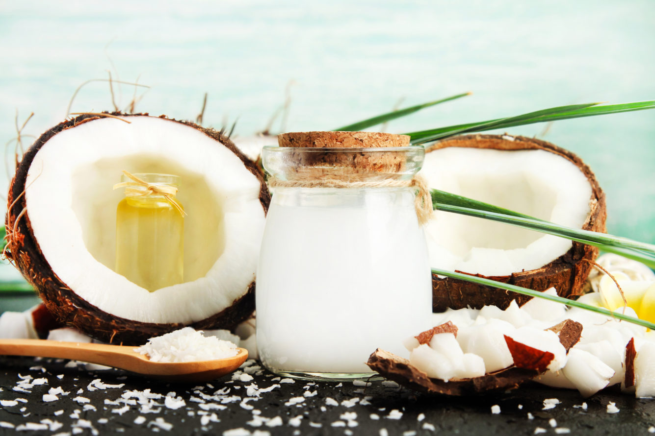 Coconuts with jar of Coconut Milk and Spoon full of Coconut Oil