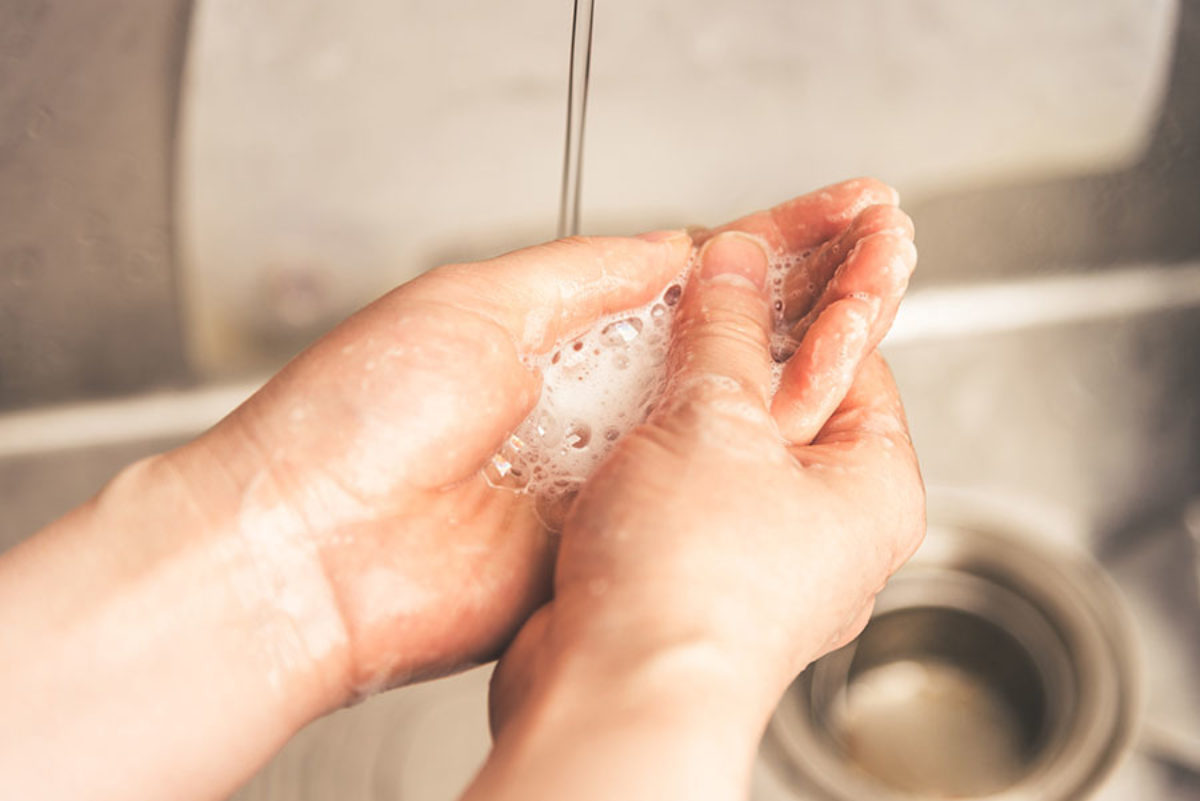 Person washing soapy hands under tap